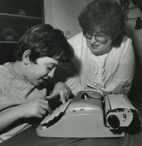 Woman and boy working on a typewriter, ca.1982 thumbnail