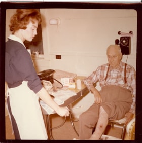 Nurse tending to an injury, [196-] thumbnail