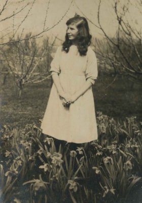 Dorothy Rawlins standing in a flower garden, [1910] thumbnail