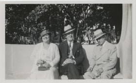 Two men and a woman on a bench, [193-?] thumbnail