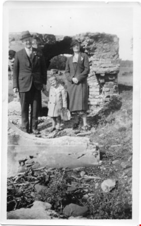 A man, woman and child in front of a stone structure, [between 1920 and 1940] thumbnail