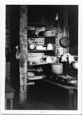 Way Sang Yuen Wat Kee & Co. kitchen with table, two ring gas burner, and shelves, 1975 thumbnail