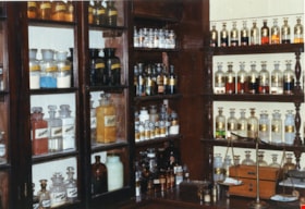 Apothecary bottles on shelving inside Burnaby Village Museum Pharmacy, [198-] thumbnail