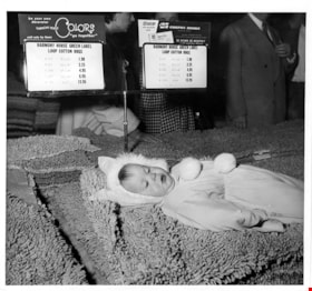 Child lying on pile of rugs, 5 May 1954 thumbnail