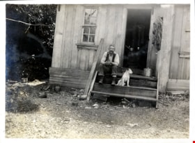 Man with dog on steps of cabin, [c. 1919] thumbnail