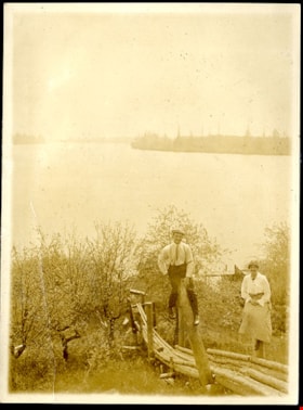 Man and woman perched on posts, [191-] thumbnail