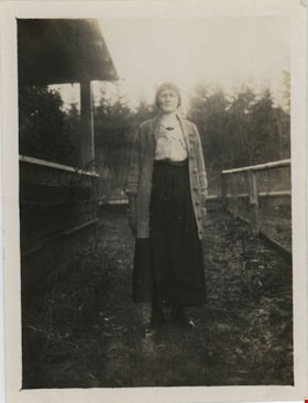 Woman standing outside of Love farmhouse, [191-] thumbnail