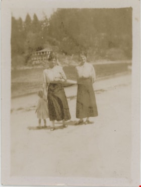 Two women walking with child on beach, [191-] thumbnail