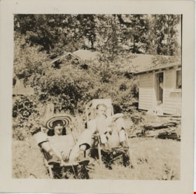 Men in lawn chairs outside cabin, [194-] thumbnail